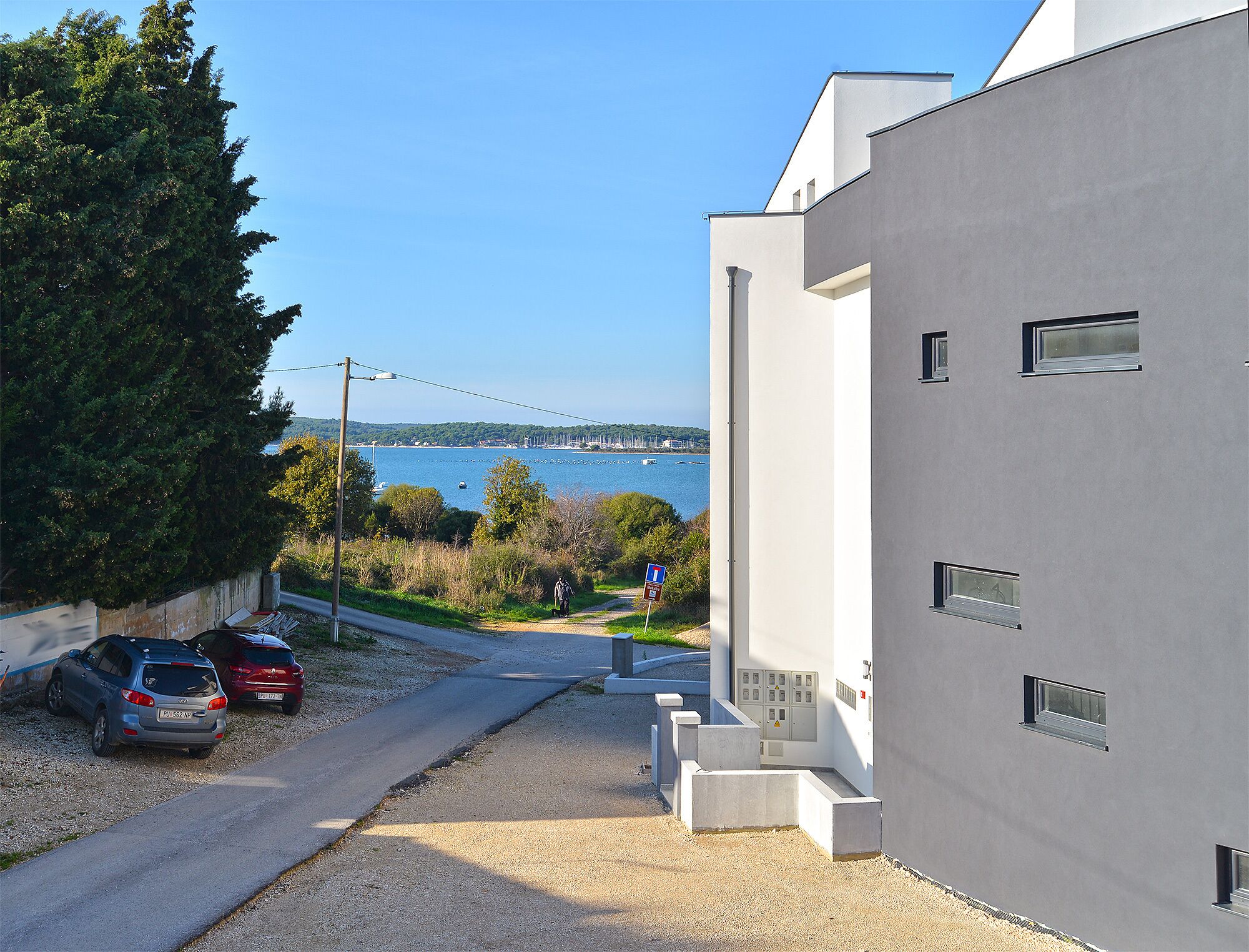 A modern building with a view of a body of water and parked cars.
