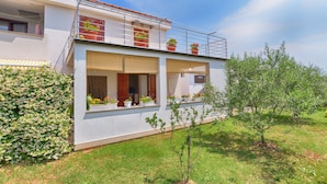 A modern two-story house with a balcony, potted plants, and a small tree in the yard. - Apartment 1983 (Fazana)