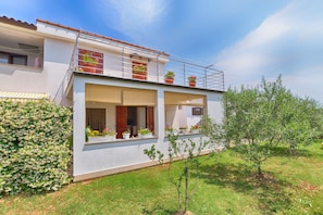 A modern two-story house with a balcony, potted plants, and a small garden. - Apartment 1983 (Fazana)