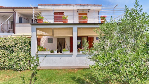 A two-story building with a balcony, potted plants, and a clear sky. - Apartment 1983 (Fazana)
