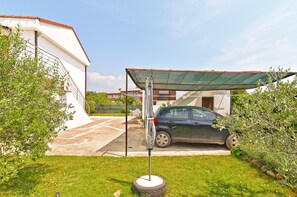 Un coche estacionado bajo una zona techada, con un inflador de neumáticos en primer plano.