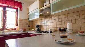 Una cocina con encimera de mármol, estufa a gas, cafetera y lavabo.