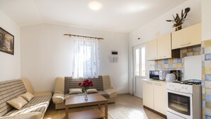 Una sala de estar moderna con un sofá, una mesa de centro y una zona de cocina con estufa y microondas.