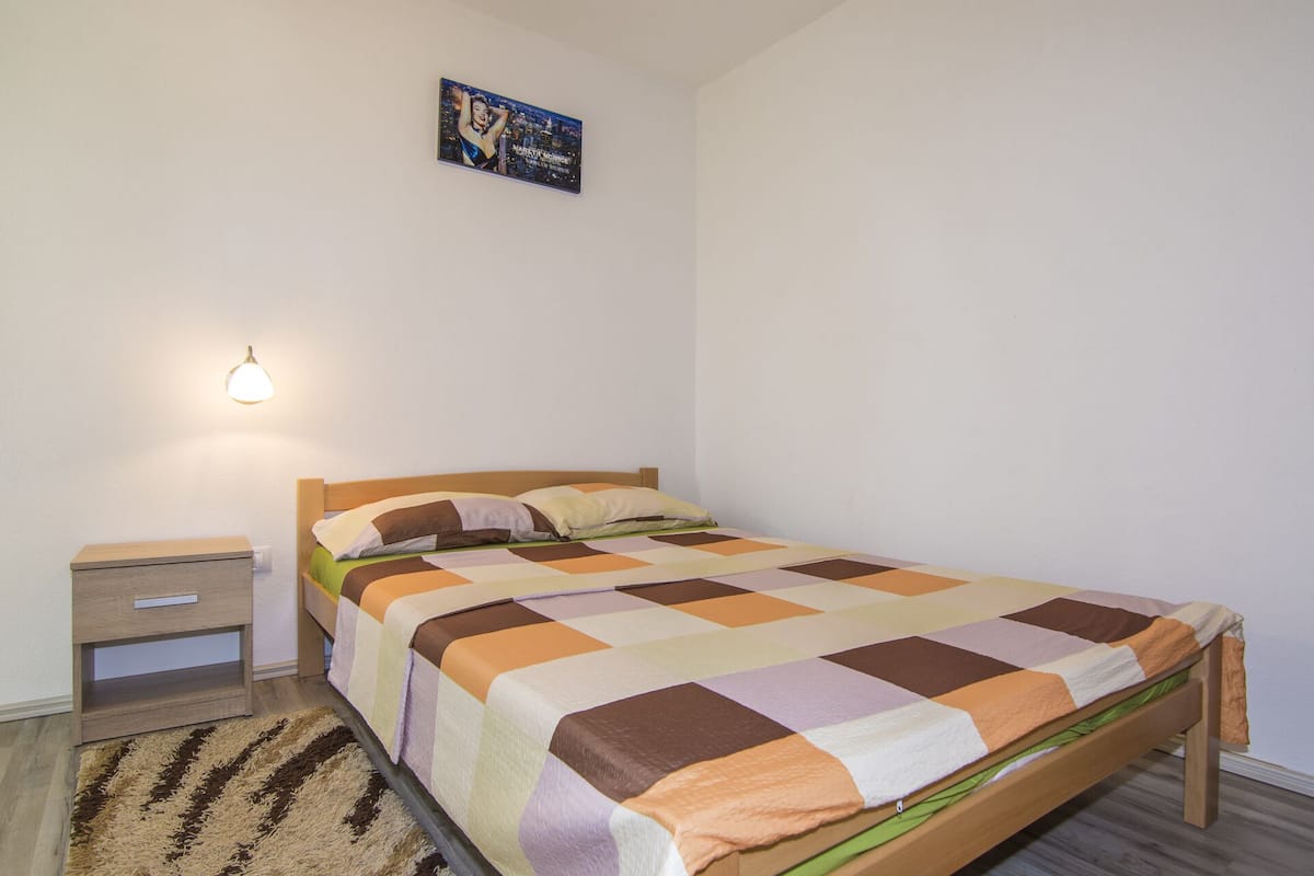 A bedroom with a bed, a nightstand, a lamp, and a poster on the wall.