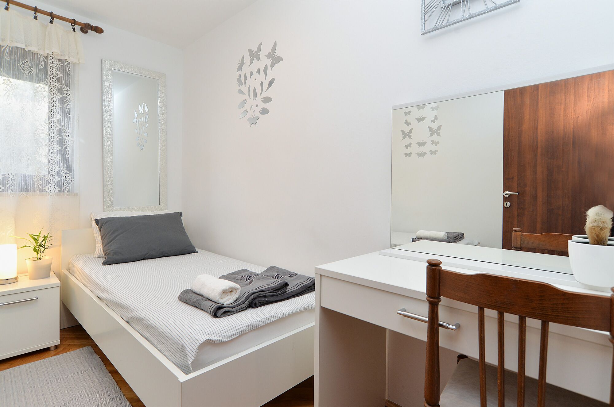 Ein Schlafzimmer mit Bett, Nachttisch, Lampe und Spiegel.