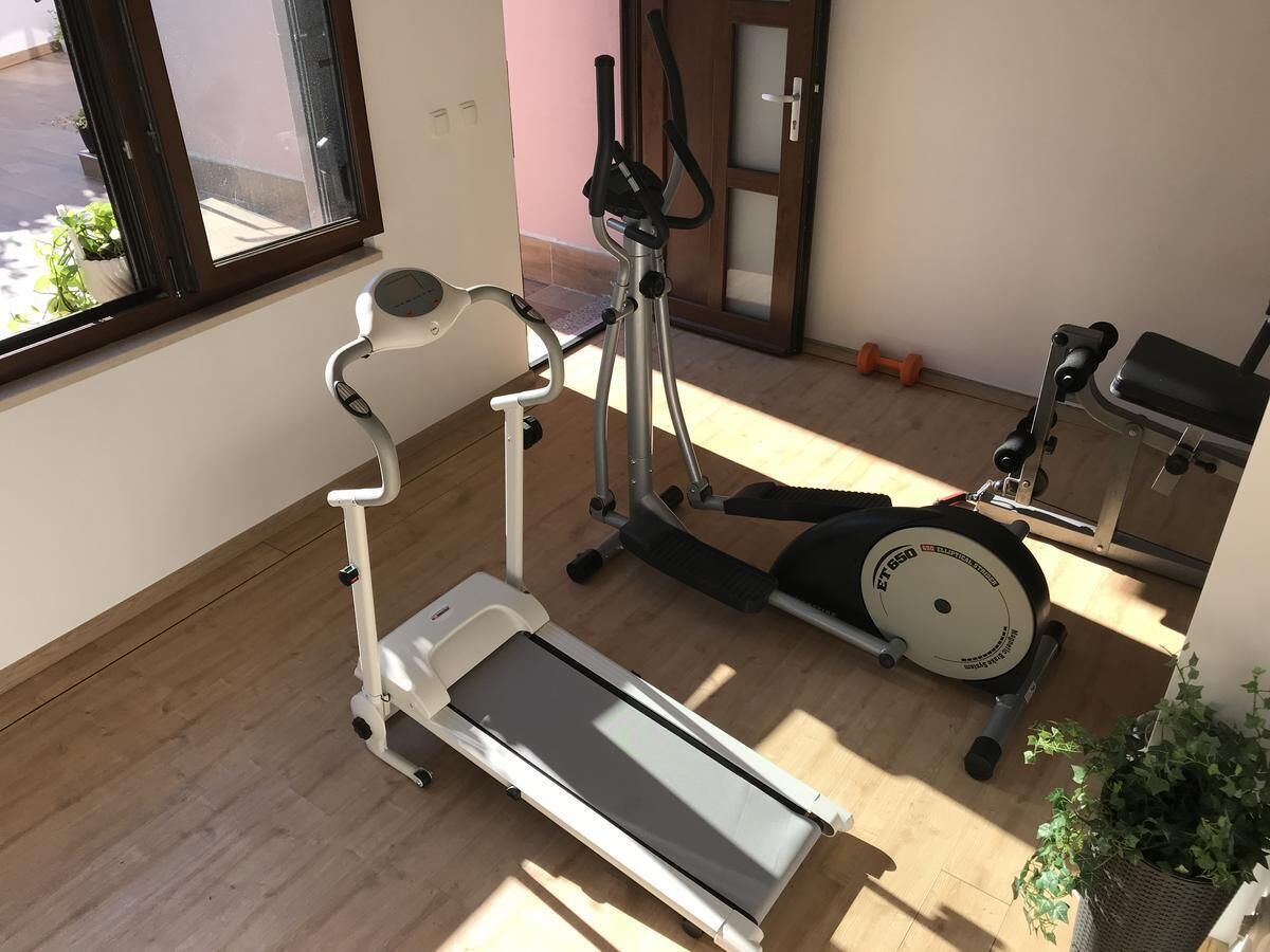A home gym with a treadmill, elliptical, and stationary bike.