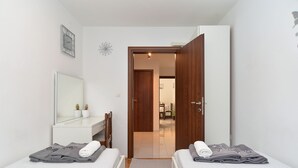 Ein Schlafzimmer mit zwei Betten, einem Spiegel, einer Kommode und einer Tür zu einem anderen Raum.