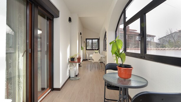Ein Balkon mit Glastür, einem Tisch mit Stühlen und Topfpflanzen.