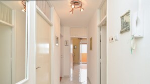 A hallway with white walls, a tiled floor, and a ceiling light fixture. - Apartment 1987 (Pula)