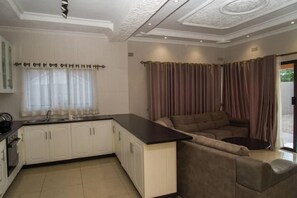 A modern kitchen with white cabinets, a black countertop, and a built-in oven. - 848 Guest House (Victoria Falls)