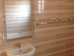 A bathroom with a sink, mirror, and tiled walls.