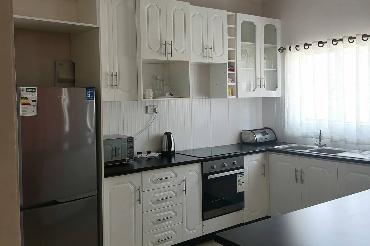 A kitchen with white cabinets, a stainless steel refrigerator, a built-in oven, and a black countertop.