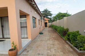 A paved pathway leading to a building with a beige exterior and a covered entrance. - 848 Guest House (Victoria Falls)