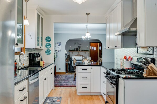 Una cucina moderna con mobili bianchi, un piano di lavoro nero e un piano cottura a gas. C'è una zona pranzo con tavolo e sedie, e un tappeto sul pavimento.