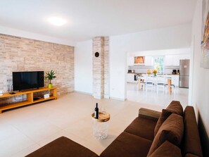 Relax in this stylish living space with a flat-screen TV, potted plant, and comfortable sofa.