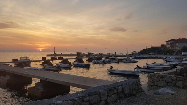 Un puerto deportivo con barcos amarrados, un muro de piedra y un puente.