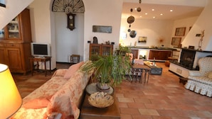 A cozy living room with a sofa, a coffee table, and a TV. There's a kitchen area with a stove and cabinets. - Peaceful Villa Stay in Rapallo (Rapallo)