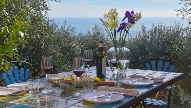 A table set for a meal with a view of the sea, a bottle of wine, and a vase with flowers. - Peaceful Villa Stay in Rapallo (Rapallo)