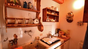 A kitchen with wooden shelves, a sink, and various kitchen utensils. - Beautiful Cottage in Pescia with Hot Tub (Pescia)