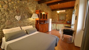 Une chambre avec un mur en pierre, un lit en bois et un bureau avec une chaise.