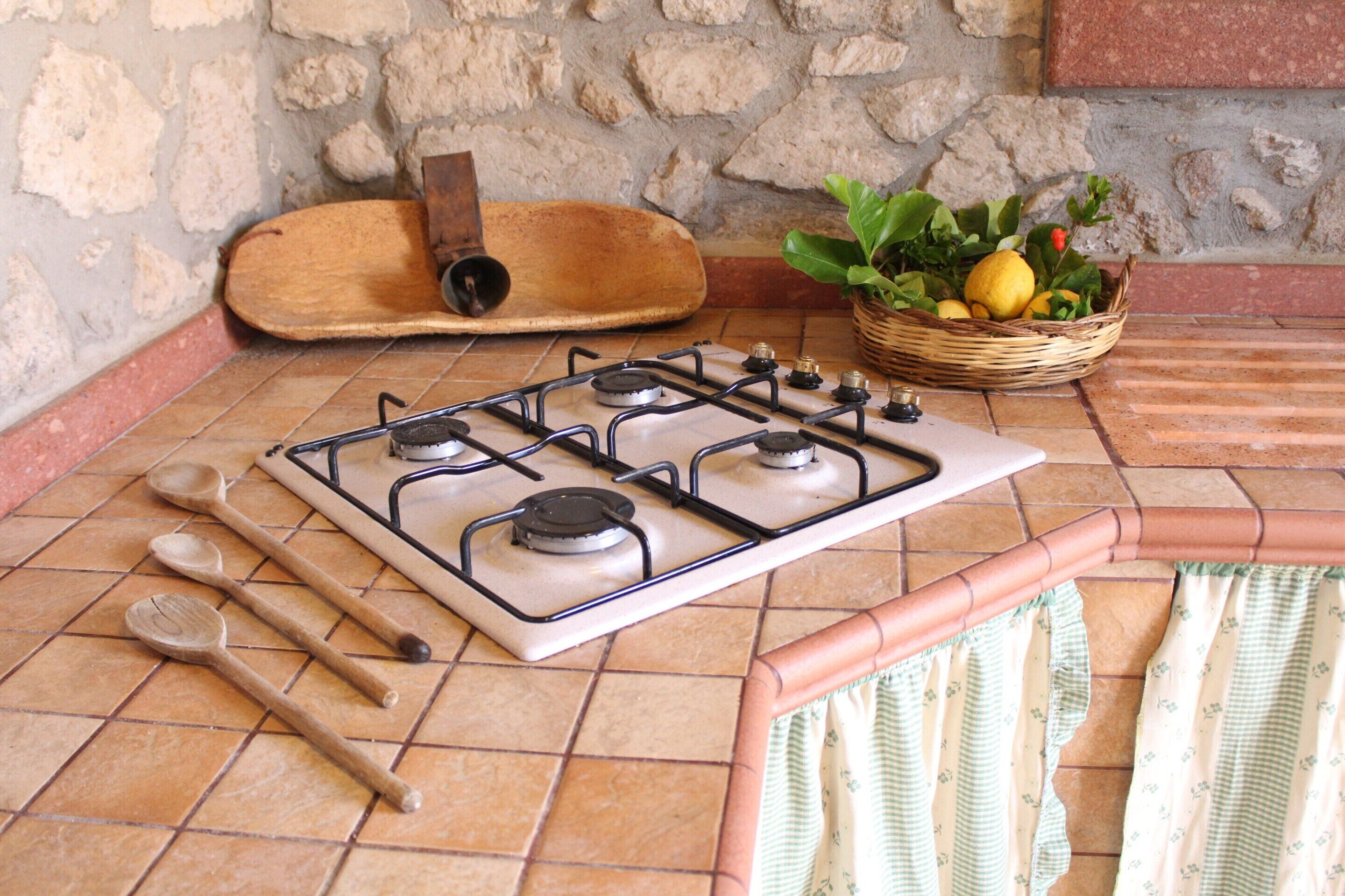 Une cuisine équipée d’une cuisinière à gaz, de cuillères en bois, d’une planche à découper en bois et d’un panier de citrons.