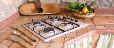 Une cuisine équipée d’une cuisinière à gaz, de cuillères en bois, d’une planche à découper en bois et d’un panier de citrons.