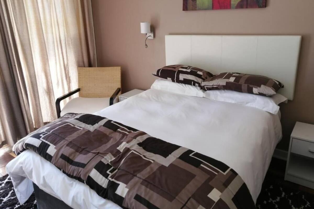 Ein Hotelzimmer mit einem großen Bett, einem Nachttisch, einem Sessel und einem Bild an der Wand.