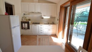 A compact kitchen with white cabinets, a refrigerator, a stove, and a dining table with chairs. - House in Pistoia Countryside (Pistoia)