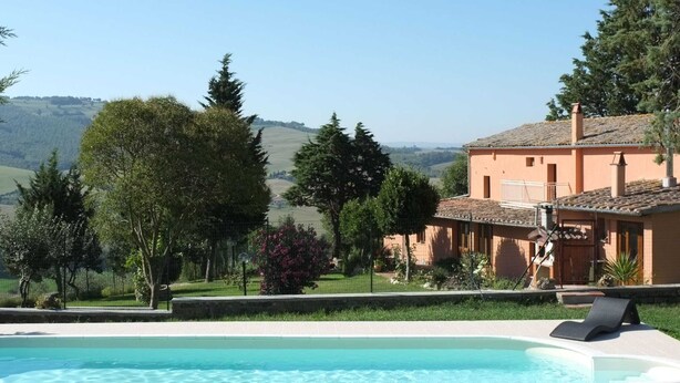 A pool with a view of a house and hills.