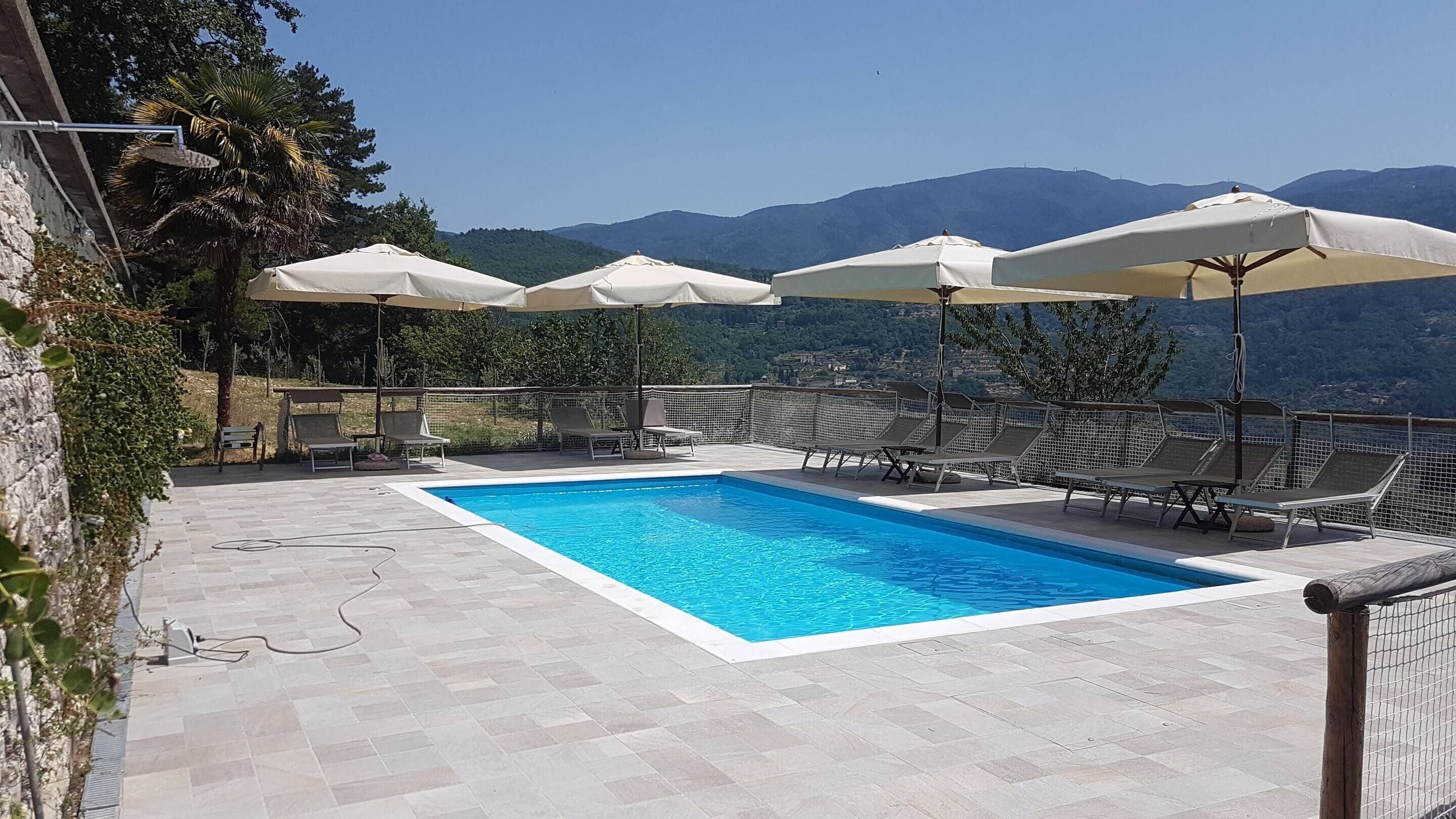 A rectangular pool with a clear blue water surface, surrounded by lounge chairs and umbrellas.