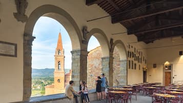 Step into a historic courtyard with a covered walkway, tables, and chairs for dining or socializing.