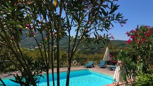 A swimming pool with lounge chairs and umbrellas, surrounded by lush greenery and hills in the background. - Your Home in a Tuscan Tower (Monterchi)