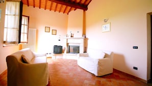 Una sala de estar con dos sofás blancos, una chimenea y un televisor.