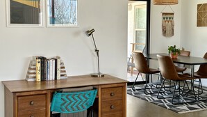 Un'area pranzo moderna con tavolo e sedie in legno, un lampadario intrecciato a sospensione e vista sull'esterno.