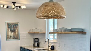 Una cucina moderna con mobili blu, una macchina da caffè e un lampadario.