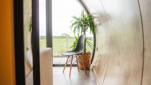 Un interior moderno con techo curvo, una silla, una planta y vistas al exterior.