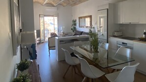 Una cucina moderna con mobili bianchi, un tavolo da pranzo in vetro e un'isola centrale.
