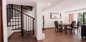 A staircase with a wooden handrail and black balusters, a dining area with a glass-top table and four chairs, and a large mirror on the wall. - HS HOTSSON Hotel Tampico (Tampico)