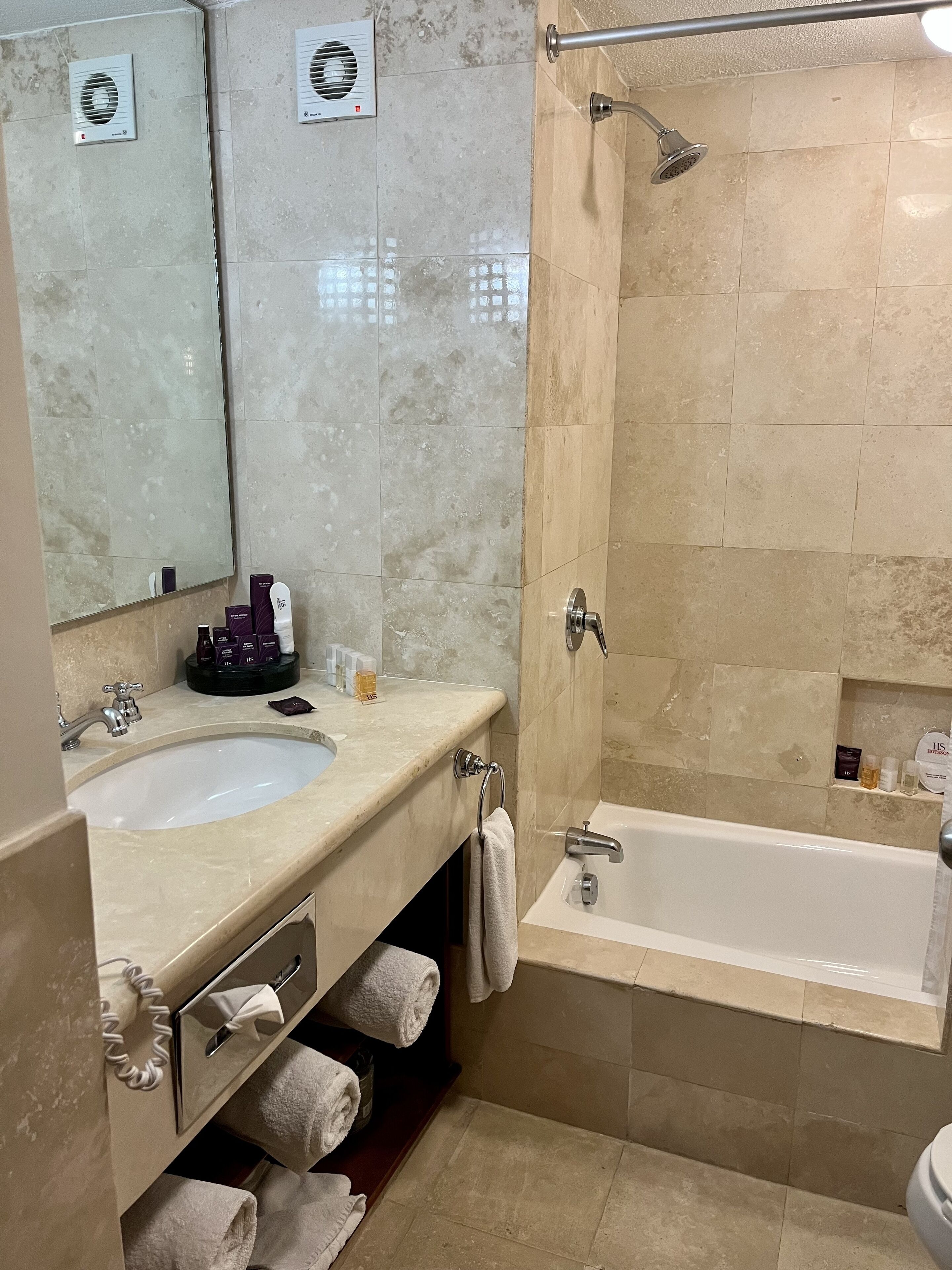 Un baño con lavamanos, espejo, toallero y zona de ducha.