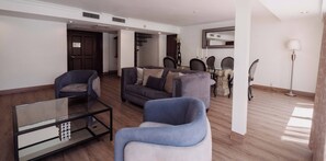 A modern living room with a sofa set, a glass coffee table, and a dining area with chairs and a table. - HS HOTSSON Hotel Tampico (Tampico)
