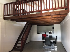 A modern kitchen with a dining area, a wooden staircase, and a view of the upper floor.