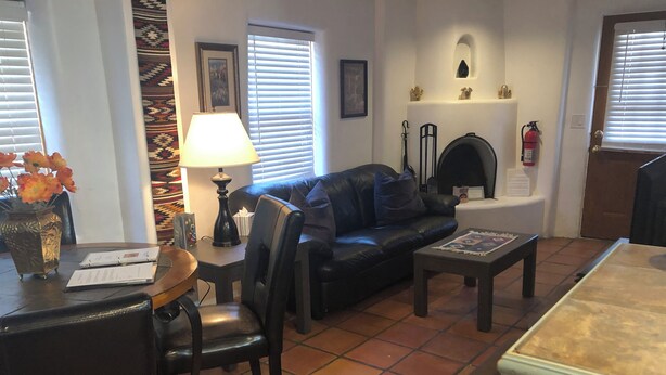 Un salon avec un canapé en cuir noir, une table basse, une lampe, une cheminée et un sol carrelé.