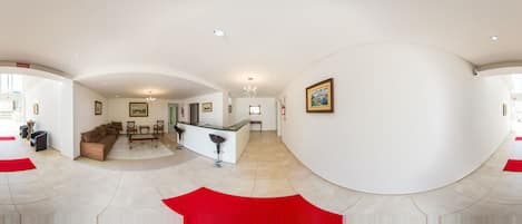A spacious living area with a modern kitchen, a dining area, and a reception desk.