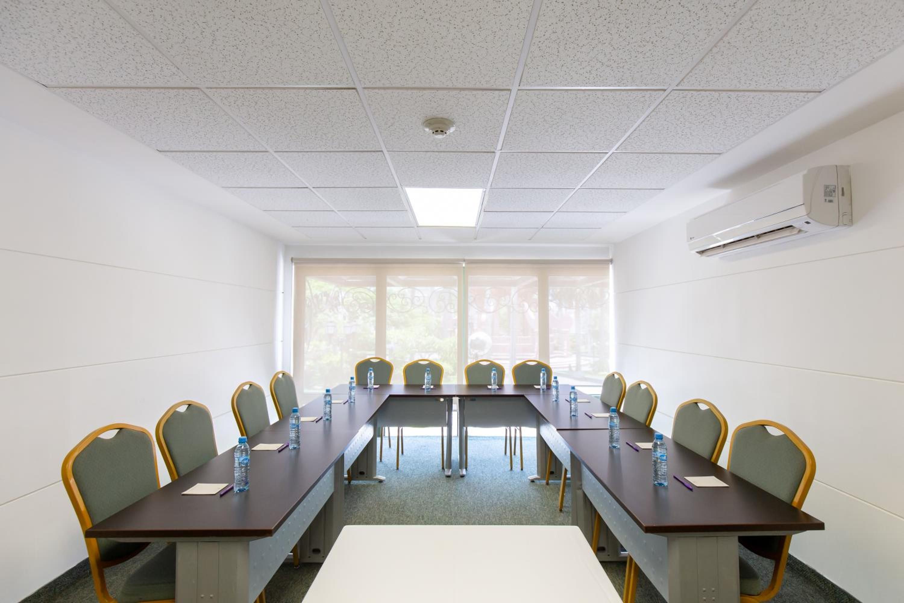 Una sala de conferencias con una mesa larga, sillas y un ventanal.