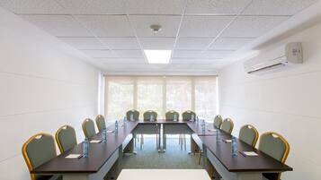 Una sala de conferencias con una mesa larga, sillas y un ventanal.