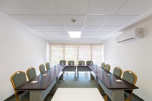 Una sala de conferencias con una mesa larga, sillas y un ventanal.