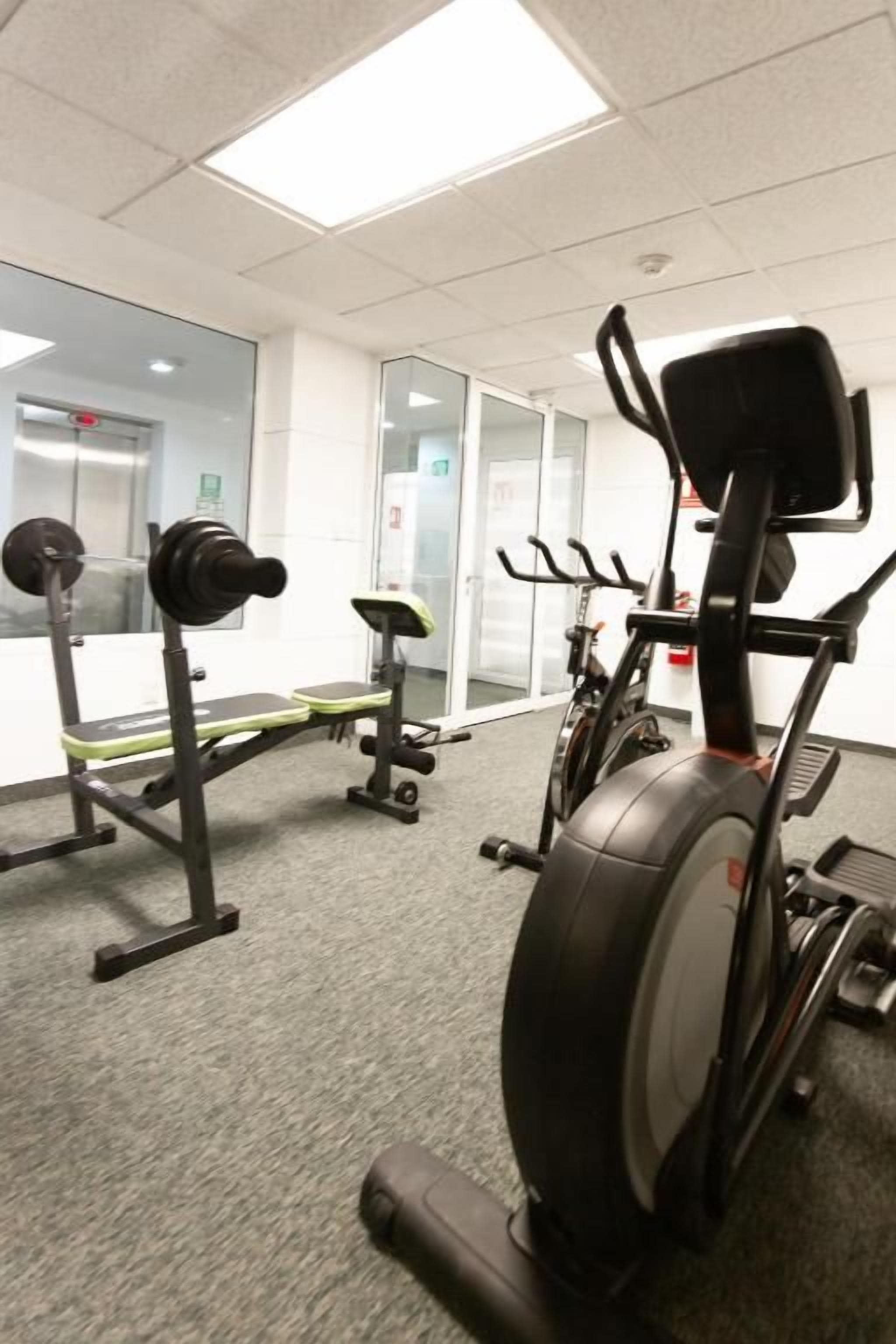 A gym with exercise equipment including a treadmill, stationary bike, and weight bench.