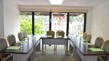 Un salón de conferencias con una larga mesa, sillas y vistas al exterior.