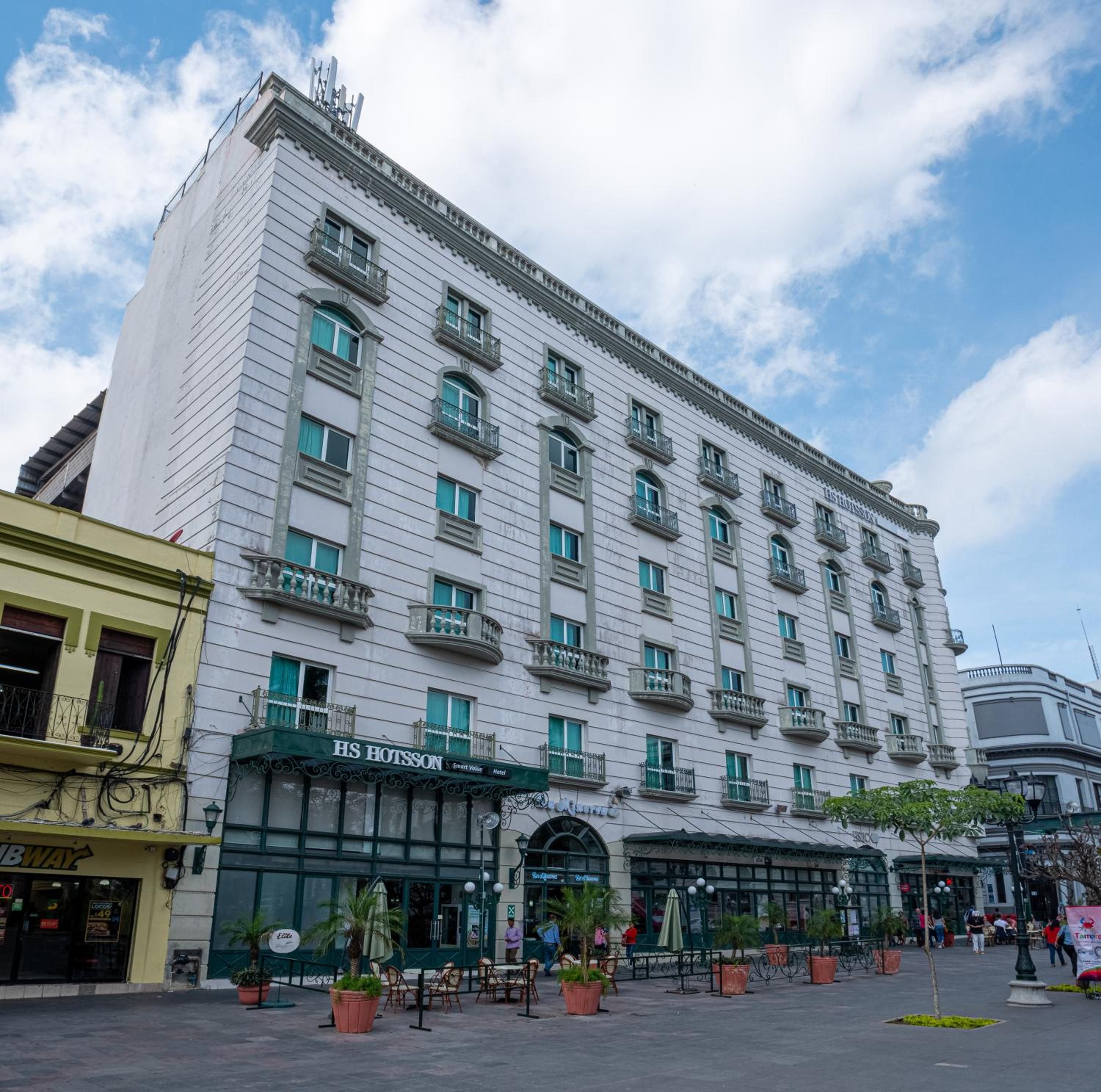 A multi-story hotel with a classic architectural style, featuring balconies and a central entrance.