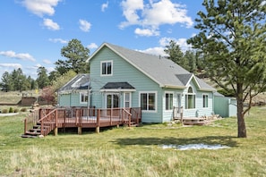 A single-story house with a deck, a front porch, and a small front yard.